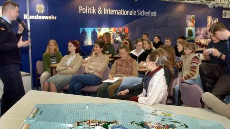 An einem Messestand der Bundeswehr in Leipzig spricht ein Jugendoffizier der Bundeswehr mit Schülern über das interaktive Spiel „Politik &amp; Internationale Sicherheit“. 