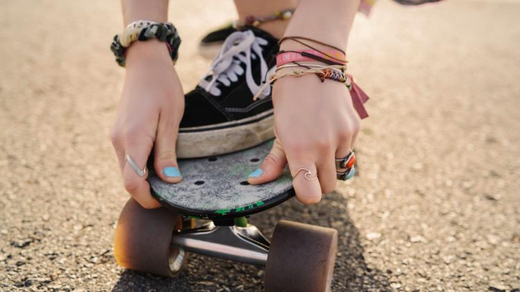 Hands of young woman holding skateboard, close-up model released Symbolfoto MPPF00812