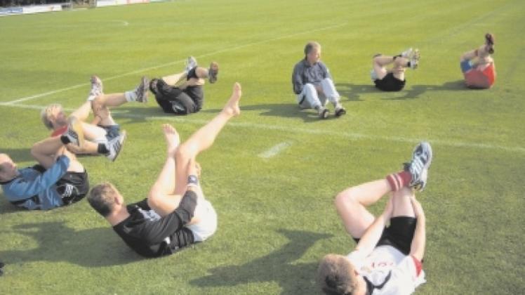 Unter den wachsamen Augen von Trainer Reinhard Jansson (sitzend) dehnen die Fußballer des SC Halen ihre müden Knochen. 