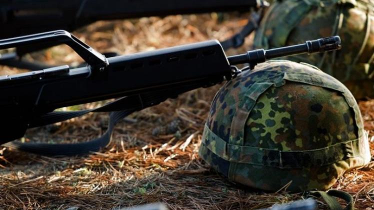 Bundeswehrhelme und Gewehre vom Typ Heckler &amp; Koch G36 liegen während einer Schießübung auf einem Truppenübungsplatz.