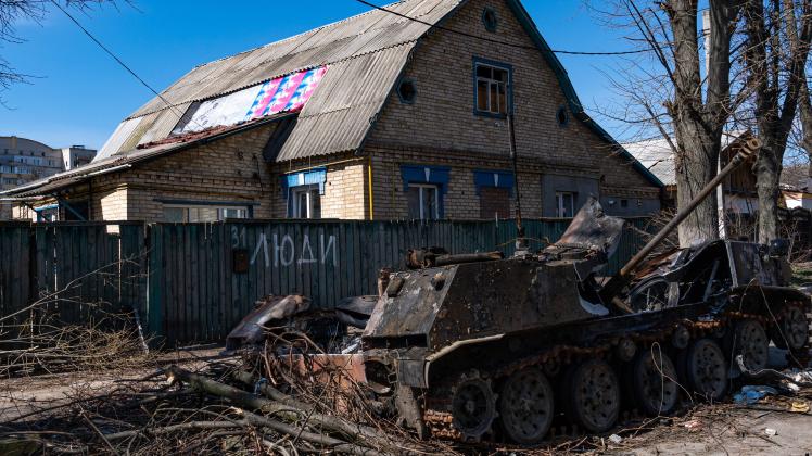 BUCHA, UKRAINE - APRIL 7, 2022 - A destroyed military vehicle is seen near a fence marked with the word People after the
