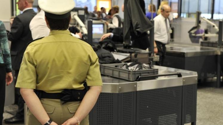 Unter den Augen einer Polizistin warten Passagiere auf die Kontrolle ihres Handgepäcks. (Archivfoto)