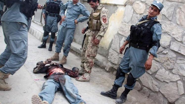 Afghanische Polizisten neben der Leiche eines Kollegen, der bei dem Taliban-Angriff getötet wurde.