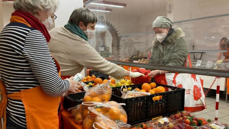Tafelmitarbeiterinnen geben einer Kundin frisches Obst und Gemüse.