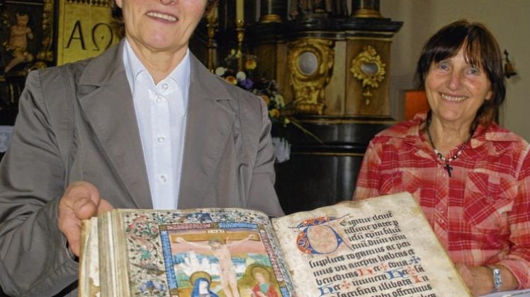 Mit dem handgeschriebenen Messbuch aus Pergament birgt die St.-Antonius-Kirche einen Schatz aus dem 15. Jahrhundert, wie Küsterin Elisabeth Riedemann (l.) Gästeführerin Ilse Jandt zeigen. Fotos: Iris Kroehnert