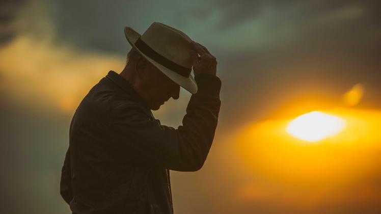 Senior man bowing in front of setting sun model released Symbolfoto OCMF01600