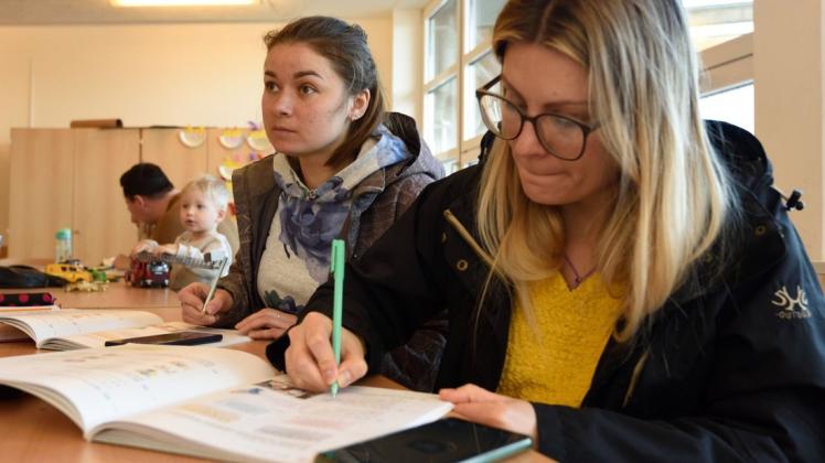 Yuliia Borovenko (links) und Anastasiia Gurenko lernen parallel mit Buch und Mobiltelefon deutsche Vokabeln.