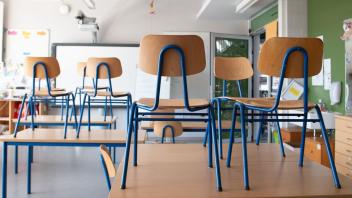 SYMBOLBILD - Stühle stehen in einem Klassenzimmer auf den Tischen. Foto: Sebastian Kahnert/dpa-Zentralbild/dpa/Symbolbild