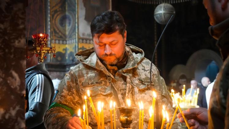 Ein ukrainischer Soldat entzündet Kerzen in der Wolodymyski-Kathedrale während der Osterfeierlichkeiten. Foto: Efrem Lukatsky/AP/dpa