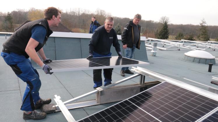 Mitarbeiter der Hagenower Firma Jessel bringen auf dem Dach der neuen Kita in Neuhaus eine der Photovoltaikplatten in Position.