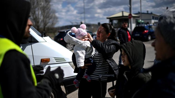 An Ukrainian refugee holds her baby before boarding a minibus taking them further inside Moldova after crossing the Ukrainian-Moldovan border into Moldova at the Palanca border crossing, southeastern Moldova on April 12, 2022. - A heartbreaking human drama is playing out along Ukraine's borders -- fleeing refugees pass the homesick going back, while others who left and then returned flee for their lives for a second time. (Photo by Christophe ARCHAMBAULT / AFP)