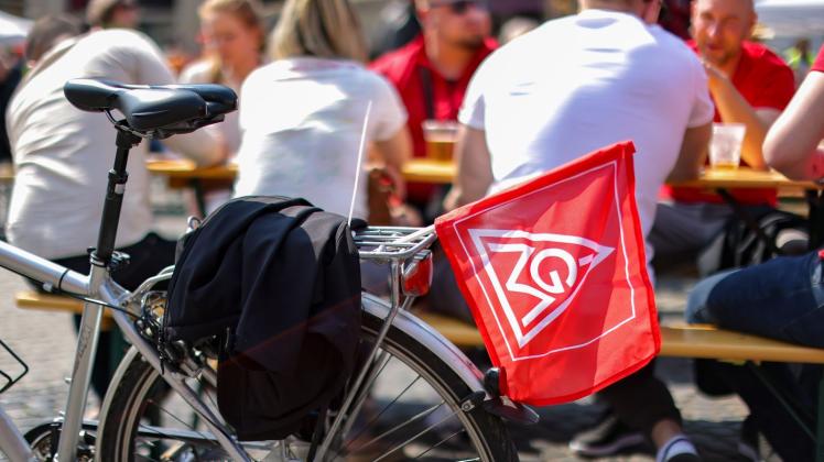 Eine Fahne der IG Metall hängt an einem Fahrrad. Foto: Jan Woitas/dpa