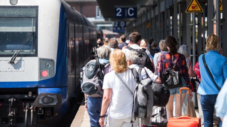 ARCHIV - Reisende gehen auf der Nordseeinsel im Bahnhof Westerland an einem Zug der Deutschen Bahn entlang. Foto: Daniel Bockwoldt/dpa/Symbolbild