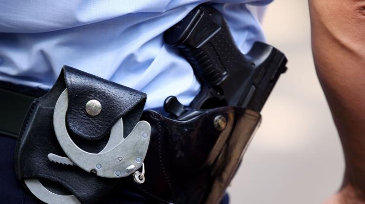 ARCHIV - Ein Polizist trägt Handschellen und seine Dienstwaffe bei sich. Foto: Oliver Berg/dpa/Symbolbild