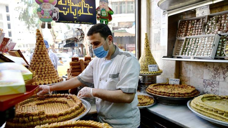 Ein Konditor arrangiert Baklava in einem Geschäft in Syrien. Muslime auf der ganzen Welt feiern das Fest des Fastenbrechens Eid al-Fitr. Foto: Ammar Safarjalani/XinHua/dpa