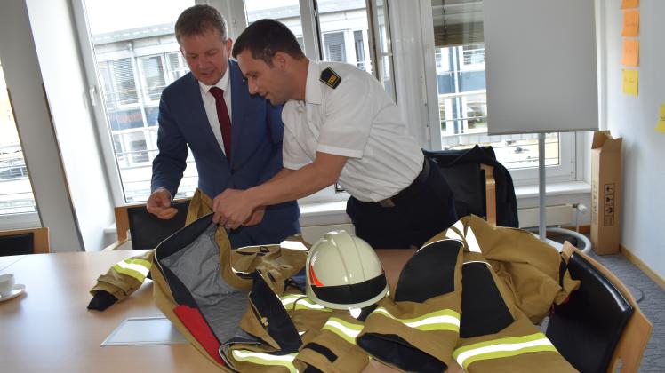 Stadtbranddirektor Dr. Stephan Jakobi erläutert Oberbürgermeister Rico Badenschier (l.) die Sicherheitsmerkmale der neuen Brandschutz-Einsatzbekleidung. 