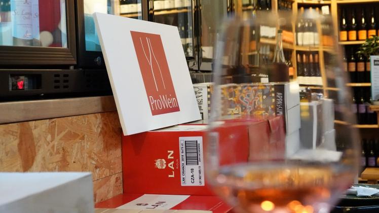 Ein Schild der Fachmesse «ProWein» steht hinter einem Weinglas. Foto: Sophie Brössler / dpa