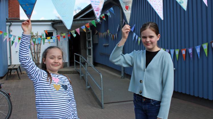 Lea Oldenburg und Martha Brockmann (r.) aus dem Güstrower Hort „Schul-Kinder-Haus Mitte“ haben beim Projekttag zur Höflichkeit eine Wimpelkette mit Höflichkeitswünschen gebastelt.