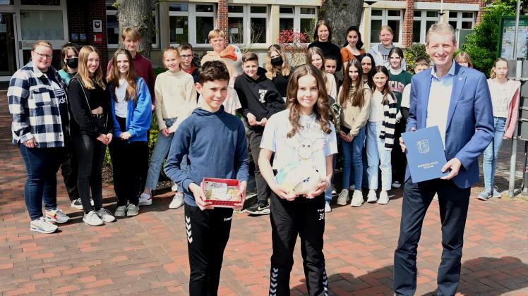 Die Klassensprecher der 7d Thierry und Luisa (von links). Bürgermeister Ralf Wessel präsentiert eine Dankesbekundung seines Amtskollegen Wojciech Gregorczyk aus Pułtusk. Begleitet wurde die Klasse von ihrer Klassenlehrerin Lena Frenzel (hinten links)
