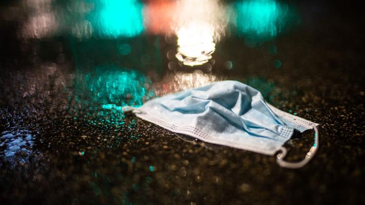 Ein Mund-Nasenschutz liegt im Regen auf der Strasse. Foto: Christoph Schmidt/dpa/Symbolbild