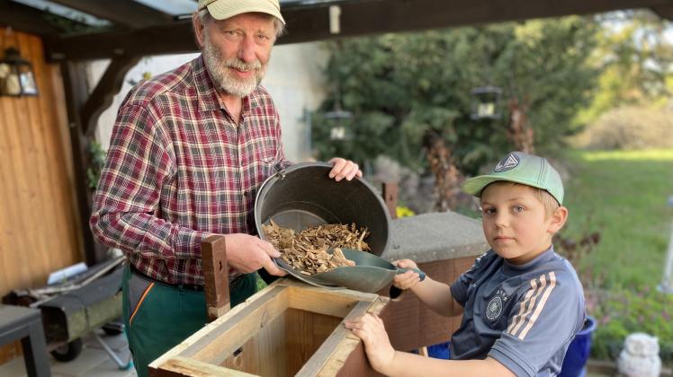 Friedhelm Scheel und sein Enkel Leon befüllen einen Nistkasten mit Rindenmulch. Der Wiedehopf baut sein Nest gerne auf diesem Material. 