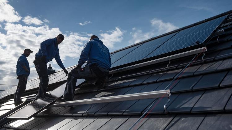 ARCHIV - Sonnendächer: Handwerker montieren Photovoltaikmodule auf dem Dach eines Wohnhauses. Foto: Marijan Murat/dpa