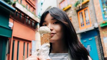 Young woman with ice cream cone in front of buildings model released Symbolfoto ASGF01500