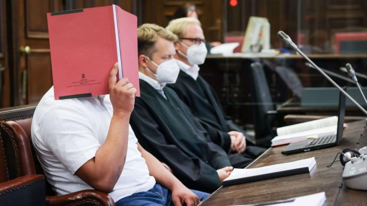 Der Angeklagte (links) sitzt am 18.10.2021 zu Beginn des Prozesses neben seinen Anwälten Dennis Dördrechter (M) und Christian Denzel im Gerichtssaal im Strafjustizgebäude.