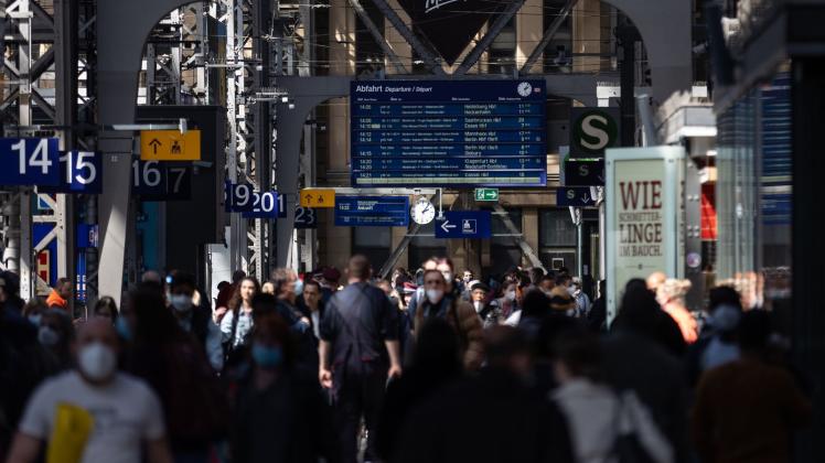 Reisende gehen durch die Bahnhofshalle in Frankfurt/Main. Die Debatte um die Maskenpflicht in öffentlichen Transportmitteln geht weiter. Foto: Hannes Albert/dpa