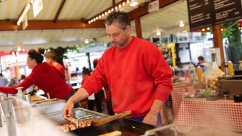 Carsten Wieland am Bratwurststand. Am frühen Nachmittag tummeln sich schon einige Osnabrücker auf der Maiwoche. Offiziell eröffnet wird sie am Abend. Vom 13. bis 22. Mai 2022 findet das Stadtfest zum ersten Mal seit drei Jahren wieder statt. Foto: Mich