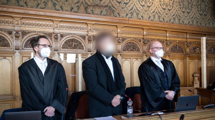 Der Angeklagte (M) steht vor Beginn des Berufungsverfahrens vor dem Bremer Landgericht mit seinen Anwälten im Gerichtssaal. Foto: Sina Schuldt/dpa