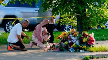 dpatopbilder - Menschen knien vor Blumen, um den Opfern tödlicher Schüsse in einem Supermarkt in Buffalo die letzte Ehre zu erweisen. Foto: Matt Rourke/AP/dpa