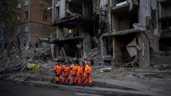 ARCHIV - Arbeiter eines Aufräumtrupps agieren vor einem Gebäude nach einer Explosion in Kiew: Die führenden westlichen Industrienationen (G7) beraten über milliardenschwere Zuschüsse für die Ukraine. Foto: Emilio Morenatti/AP/dpa