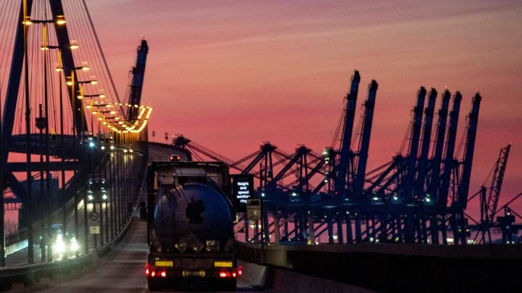Die Sonne geht hinter hochgeklappten Containerbrücken im Hafen und der Köhlbrandbrücke unter. Auf dem markanten Bauwerk im Süden der Stadt hatte es am Wochenende Wartungs- und Instandsetzungsarbeiten gegeben.
