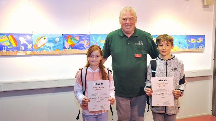 Emma und Jonah aus der Grundschule Bentwisch präsentieren gemeinsam mit Dittmar Brandt vom Rostocker Zooverein ihre Kunstwerke.