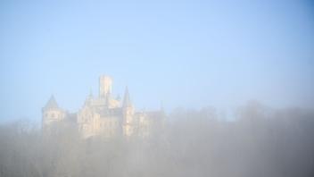 ARCHIV - Dichte Nebelschwaden ziehen am frühen Morgen bei Sonnenaufgang über das Schloss Marienburg hinweg. Foto: Julian Stratenschulte/dpa/Archivbild
