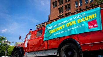 Der Schriftzug «Ohne Weihnachtsgeld brennt der Baum!» ist bei der 24-Stunden-Demonstration unter dem Motto «Wahltag ist Zahltag» vor dem niedersächsischer Landtag auf einem Banner an einem alten Feuerwehrfahrzeug zu lesen. Foto: Moritz Frankenberg/dpa