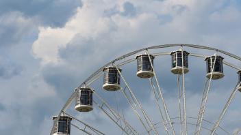 Das Riesenrad vor Wolkenformationen am Himmel. Sommerliche Temperaturen und verschiedene Musik-Acts lockten auch am Mittwoch wieder zahlreiche Besucher auf die Maiwoche 2022 in Osnabrück. Foto: Michael Gründel