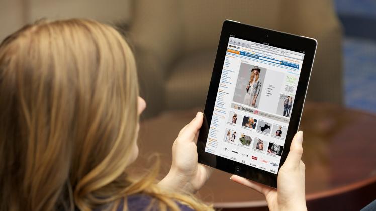 Close up view of a young Caucasian woman browsing Amazon online shopping store on an iPad 2 with wireless internet connection (Christin Gilbert)
