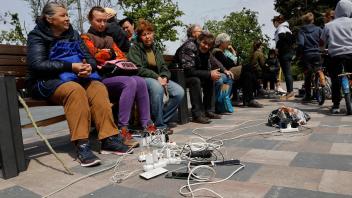 Menschen in Mariupol laden ihre Telefone auf - das Gebiet in der Ostukraine steht unter der Regierung der sogenannten Donezker Volksrepublik. Foto: Alexei Alexandrov/AP/dpa
