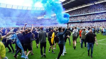 Fans von Manchester City stürmten nach dem Gewinn der Meisterschaft das Spielfeld: Die meisten friedlich. Foto: Martin Rickett/PA Wire/dpa
