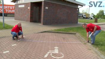 Frank und Manni messen einen Parkplatz für Menschen mit Handicap aus