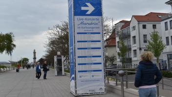 Eine Säule auf der Promenade Warnemünde informiert über die Konzerte im Kurhausgarten