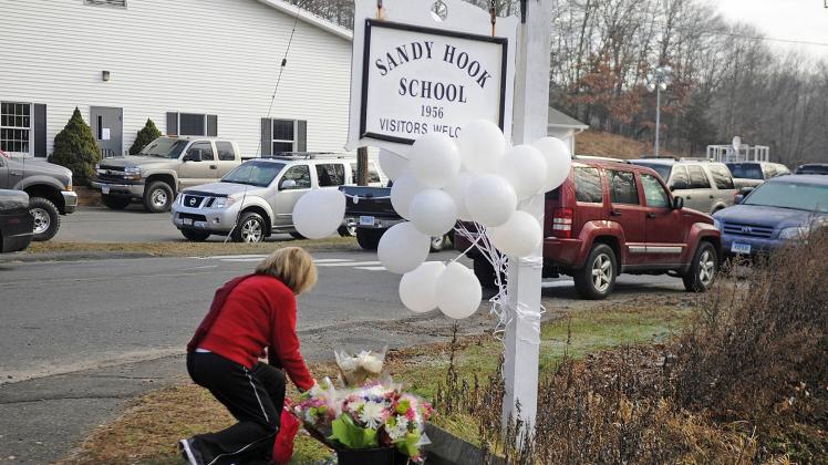 December 15, 2012 - Newtown, CT, USA - A woman places a memento at the sign for Sandy Hook Elementar