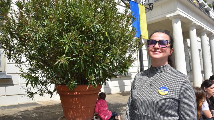 Eine Frau steht vor der ukrainischen Flagge am Rathaus in Wismar.