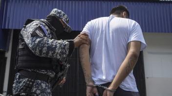 ARCHIV - Ein vermummter Polizist in begleitet einen mutmaßlichen Mitglied einer Bande nach dessen Festnahme in San Salvador. Foto: Camilo Freedman/dpa