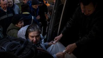 April 7, 2022, Severodontesk, Ukraine: A woman grabs grocery bags offered by a volunteer from the Czech non-governmental