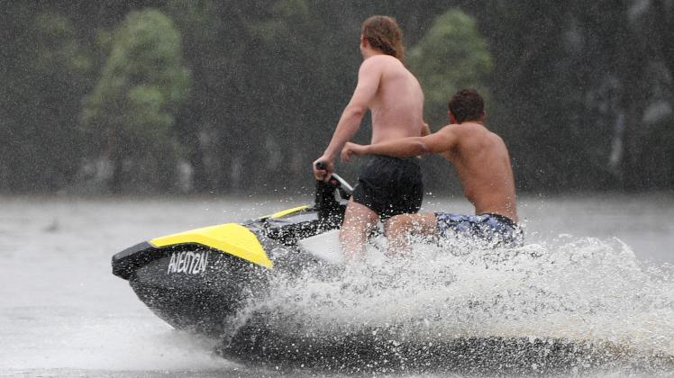 Australien, Überschwemmungen in New South Wales  FLOODS NSW, People ride a jetski and surfboards on a flooded Passmore r