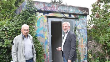 Schließen die Tür auf zu einem Erinnerungsort: Dr. Norbert Boese (links) und Dr. Carsten Jöhnk an einem der Eingänge zum ehemaligen Luftschutzbauwerk in Annenheide.