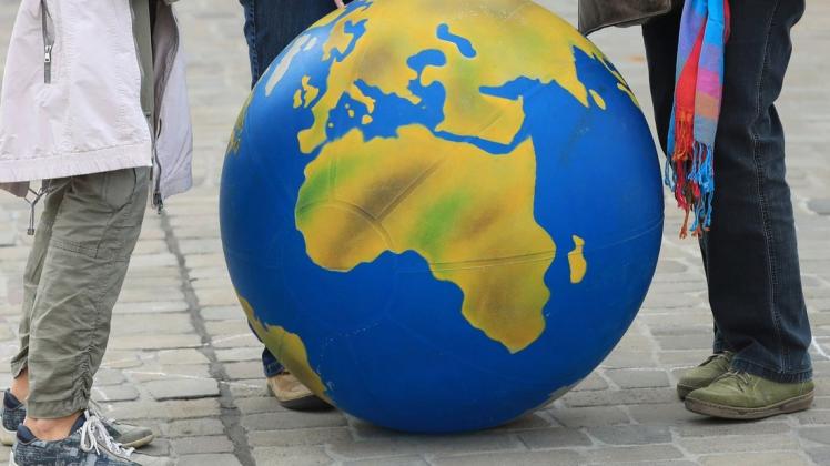 Aktivisten der Klimaschutzbewegung Fridays for Future stehen mit Plakaten und einem Ballon, der eine Weltkugel darstellt, auf der Straße.